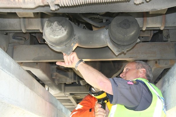 A Police Vehicle Safety Officer (VSO) Ã½a qualified mechanic Ã½ finds a problem with a bus's rear brake cylinder during a safety inspecti